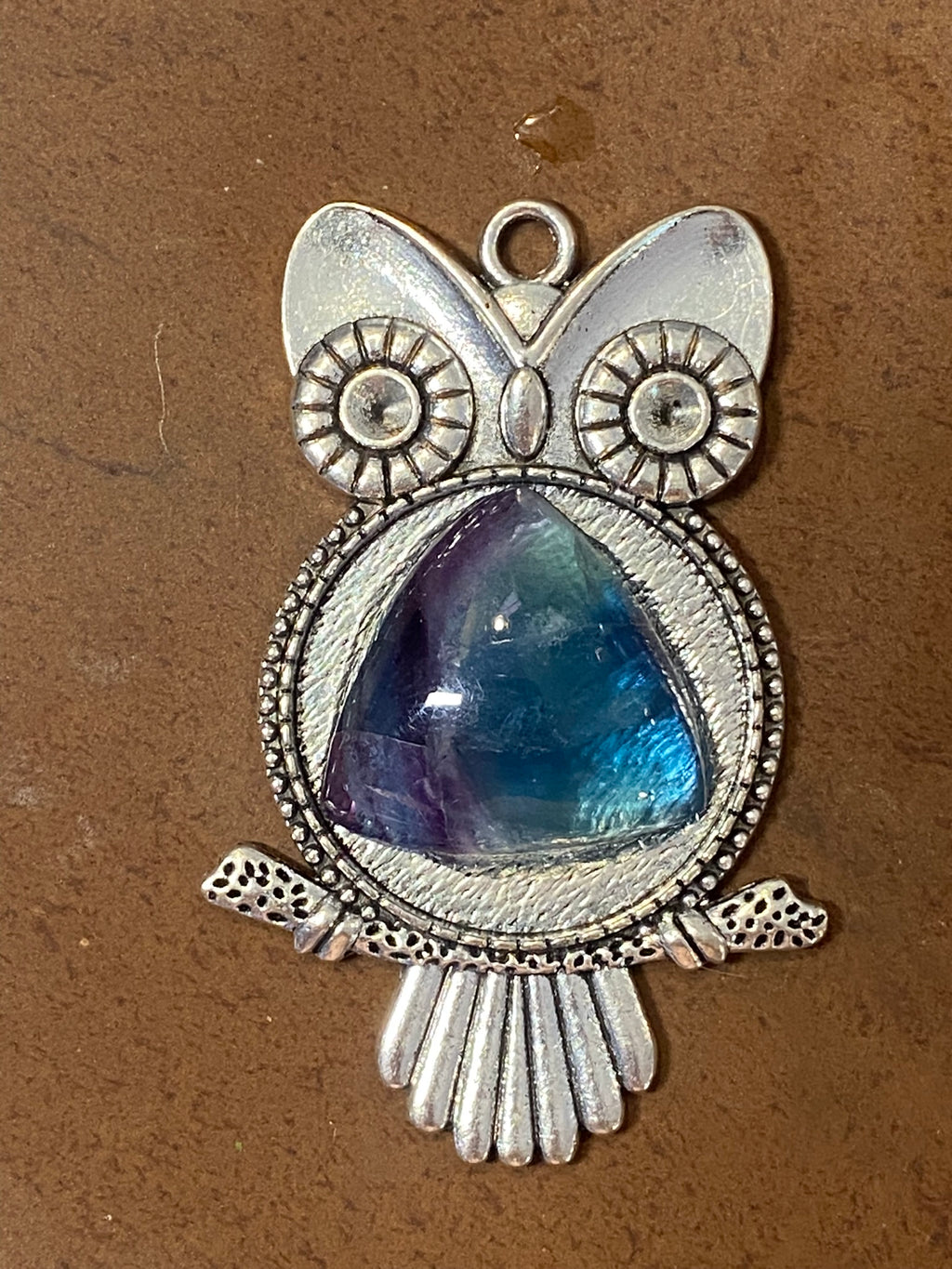 Silver owl pendant with a blue florite gemstone on a brown background