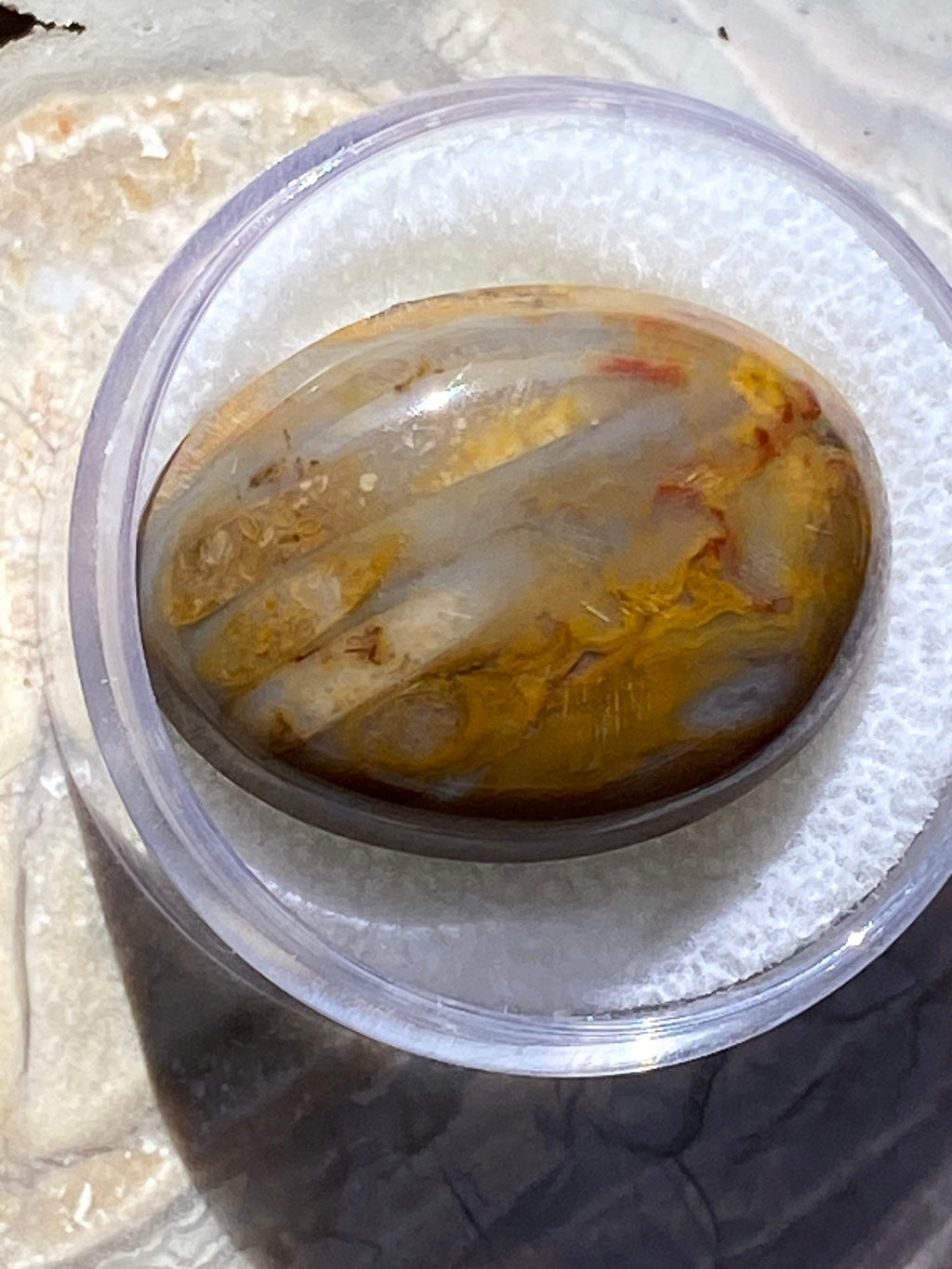 Marbled stone n a clear container on a textured surface