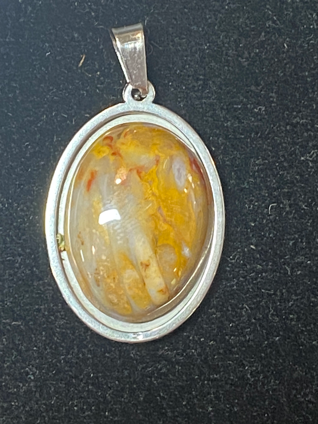 Silver pendant with an oval stone on a dark background
