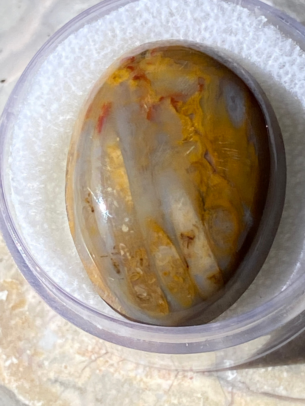 Close-up of a container with a yellowish agate on a white background